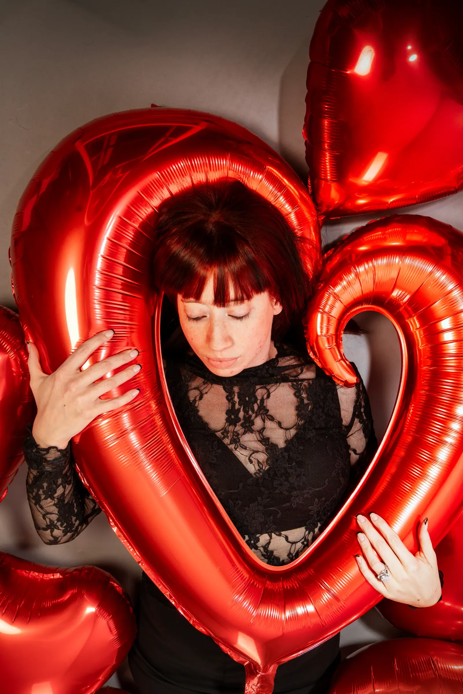 Relaxed boudoir portrait reclining among heart-shaped balloons