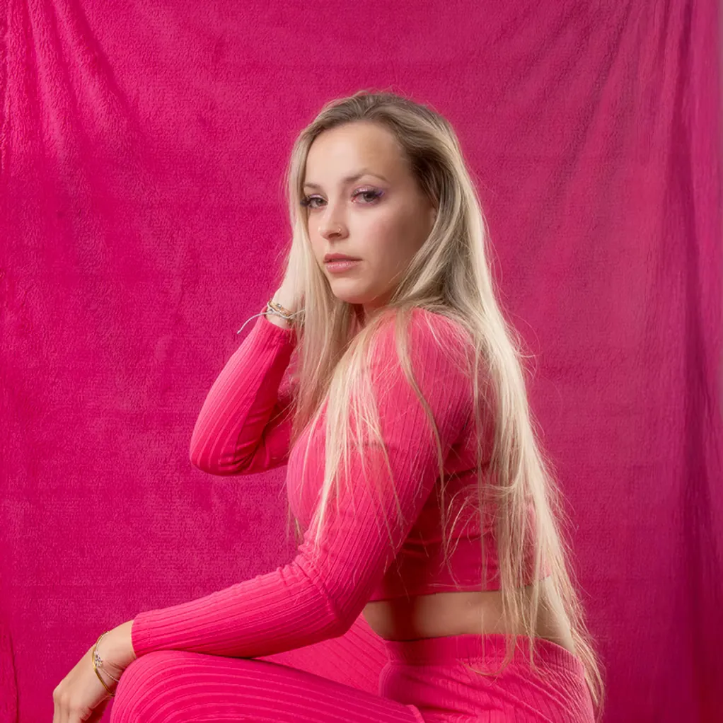 Editorial fashion portrait in vivid magenta against a matching studio backdrop