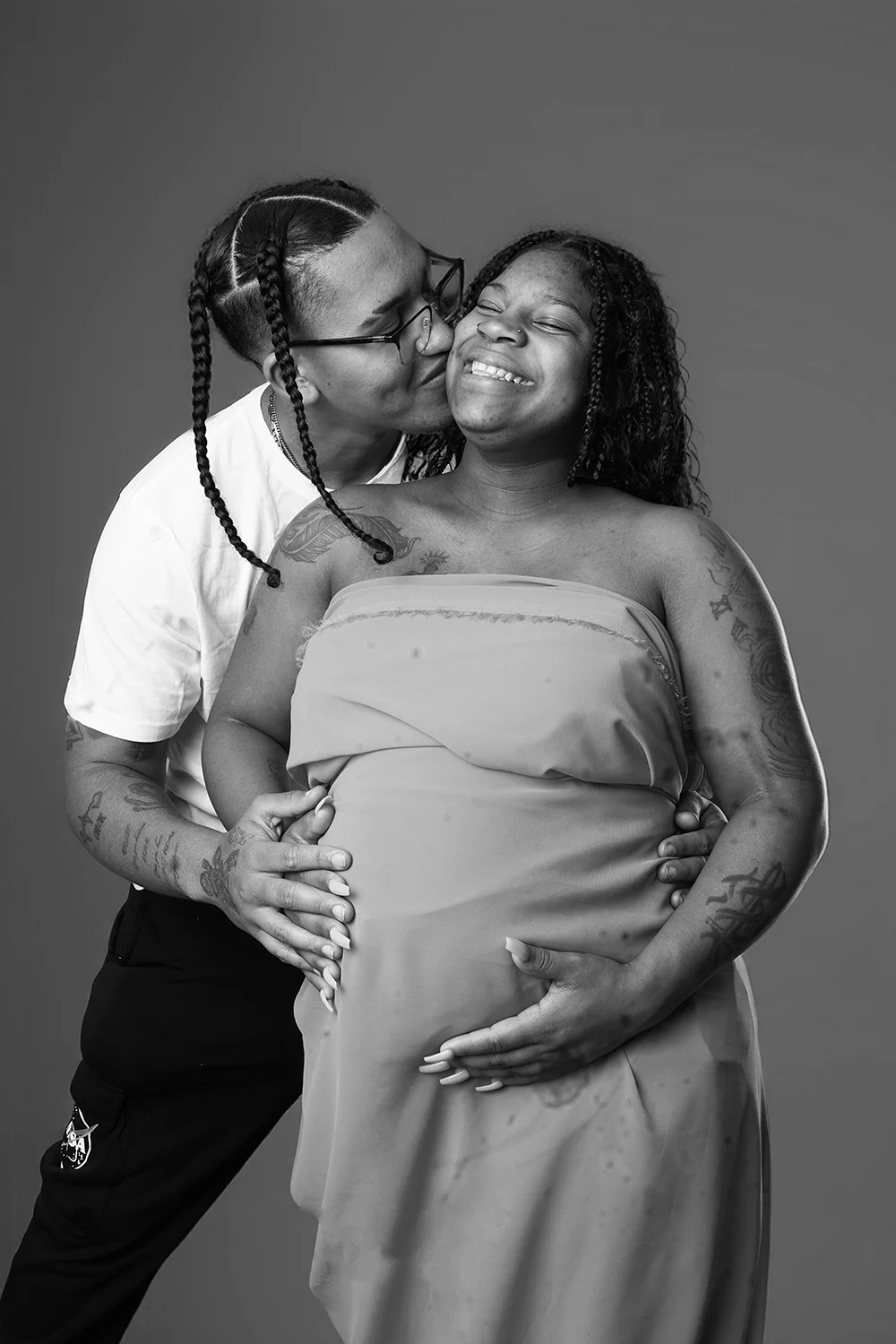 Tender black-and-white maternity portrait with a partner embracing the expectant mother