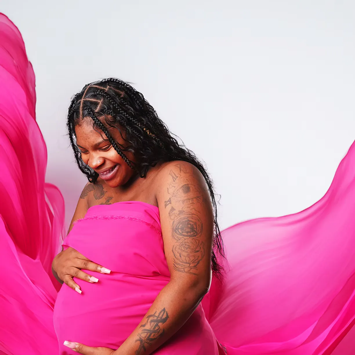Expectant mother in flowing magenta fabric in a Long Island studio portrait